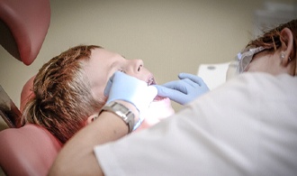 dentist examining little boy’s mouth 