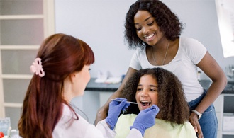 Pediatric dentist in Hillsboro performing exam on child with parent