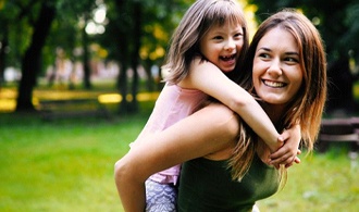 mother giving young daughter a piggyback ride 