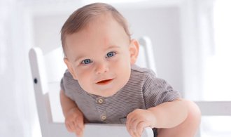 toddler boy trying to climb out of white chair 