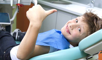 Smiling preteen boy in dental chair giving thumbs up