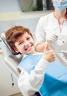 boy in dental chair giving thumbs up