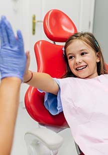girl in dental chair giving high-five