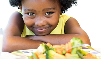 A young girl looking at healthy food on a plate