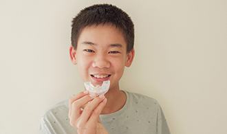 A young boy holding a mouthguard