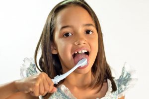 child brushing her tongue.