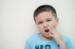 little boy holding jaw from toothache