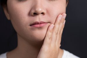 close-up kid holding jaw in pain