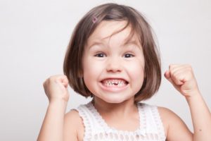 Excited girl with missing tooth smiles at her Hillsboro pediatric dentist