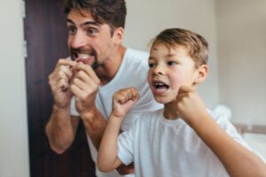 Dad and son flossing their teeth together