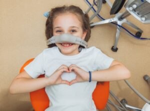 Child doing heart hands while getting laughing gas
